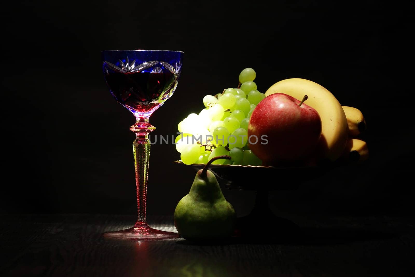 Still life with nice vintage wine glass near fruits on dark background