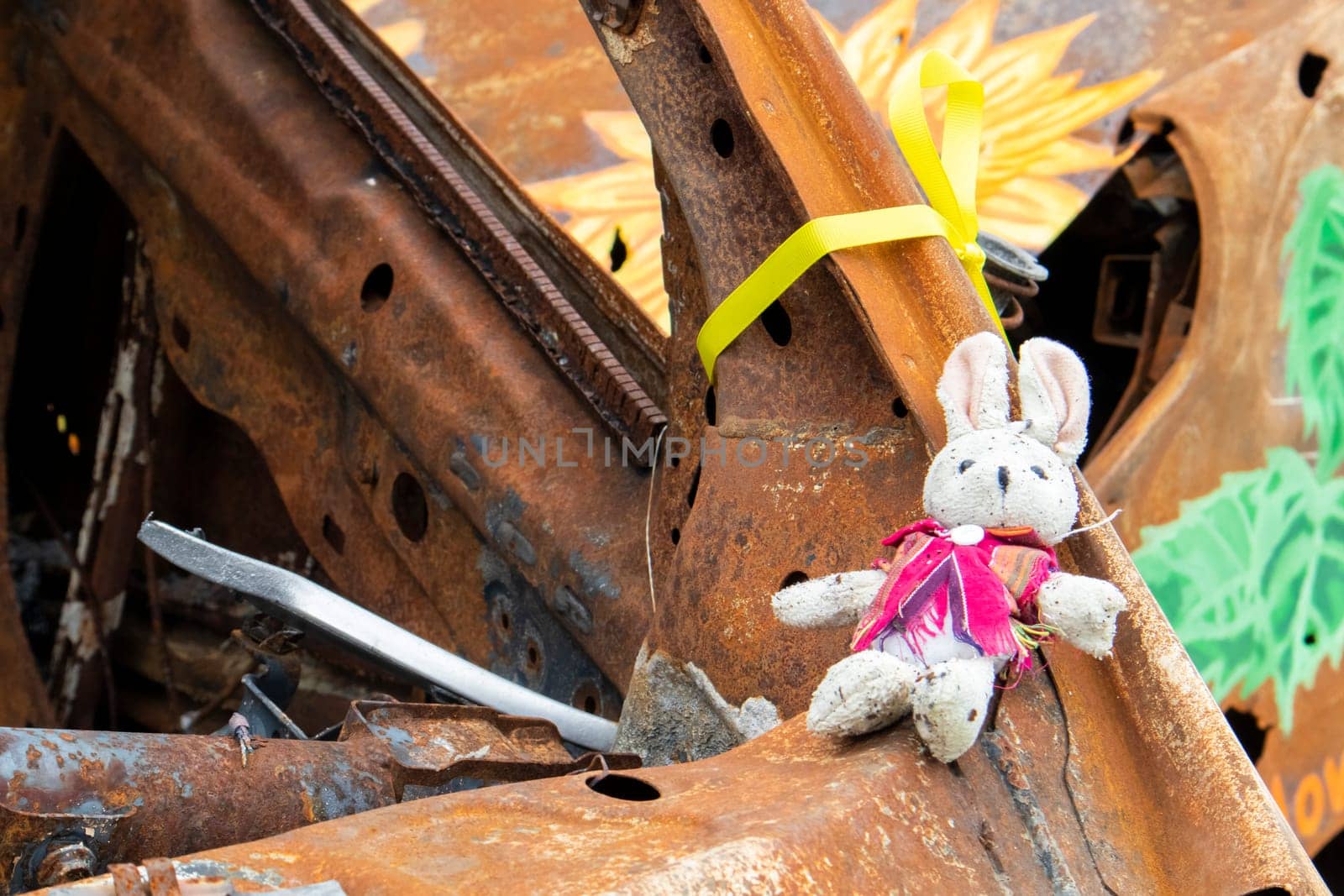 Close-up of a child's toy in ruins after a fire. A soft toy among the cars that burned down as a result of the bombing. A ruined childhood. War concept. Ukraine. Dangerous traffic accident