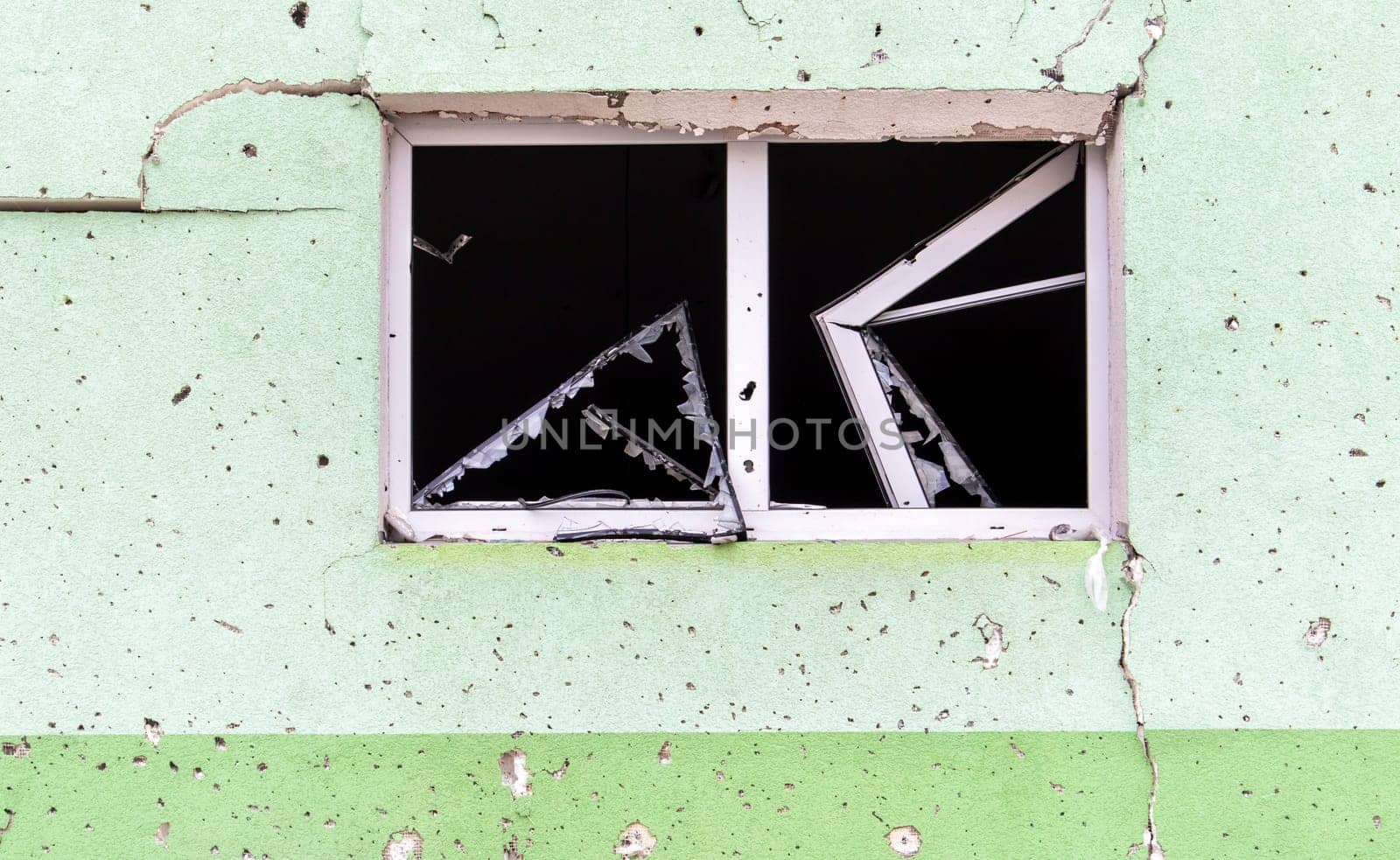 Destroyed and damaged window in the building as a result of the war. The houses were destroyed and burned by artillery during the war. Broken windows. A window destroyed by the fighting