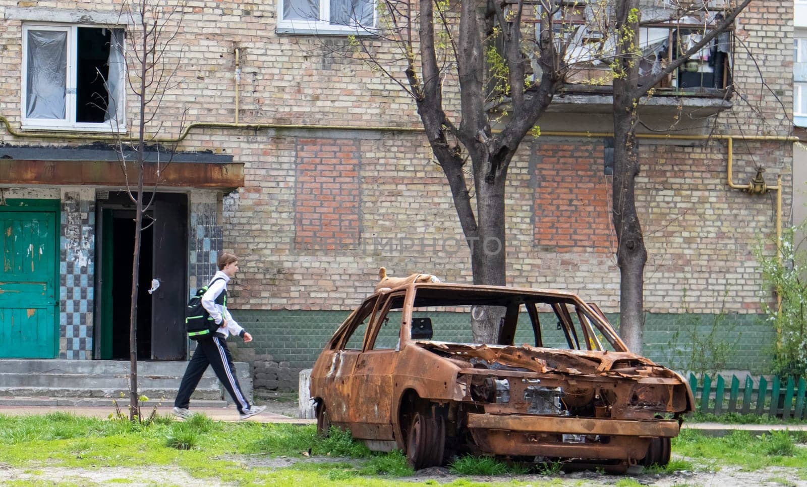 A broken car, shot by artillery, stands in the courtyard of a multi-storey residential building. War between Russia and Ukraine. The wreckage of an abandoned car. Ukraine, Kyiv - May 06, 2023