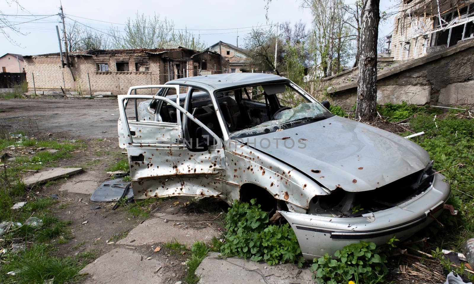 A broken Ukrainian civilian car, shot by artillery, stands in the courtyard of a destroyed house. War between Russia and Ukraine. The wreckage of an abandoned car