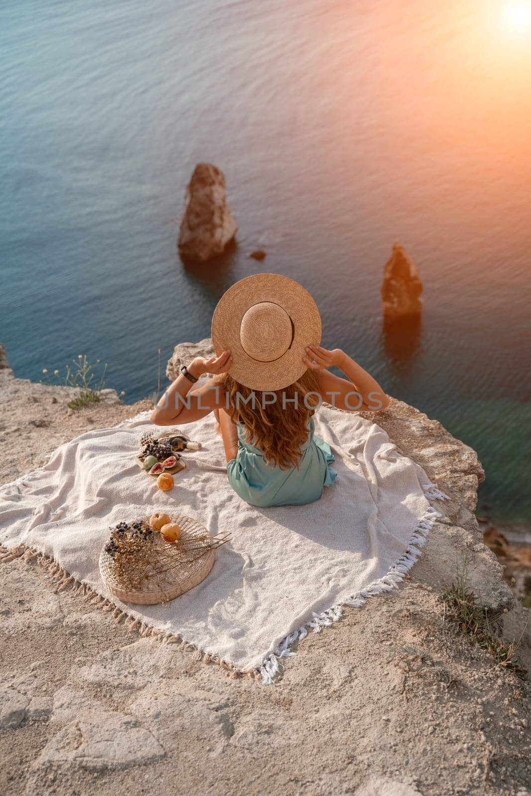 woman sea travel. photo of a beautiful woman with long blond hair in a pink shirt and denim shorts and a hat having a picnic on a hill overlooking the sea by Matiunina