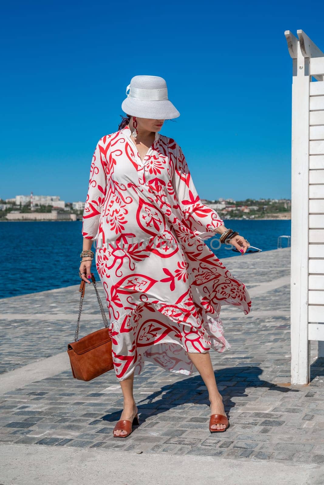 woman in a hat and dress enjoys the blue sea and summer. Welcome summer