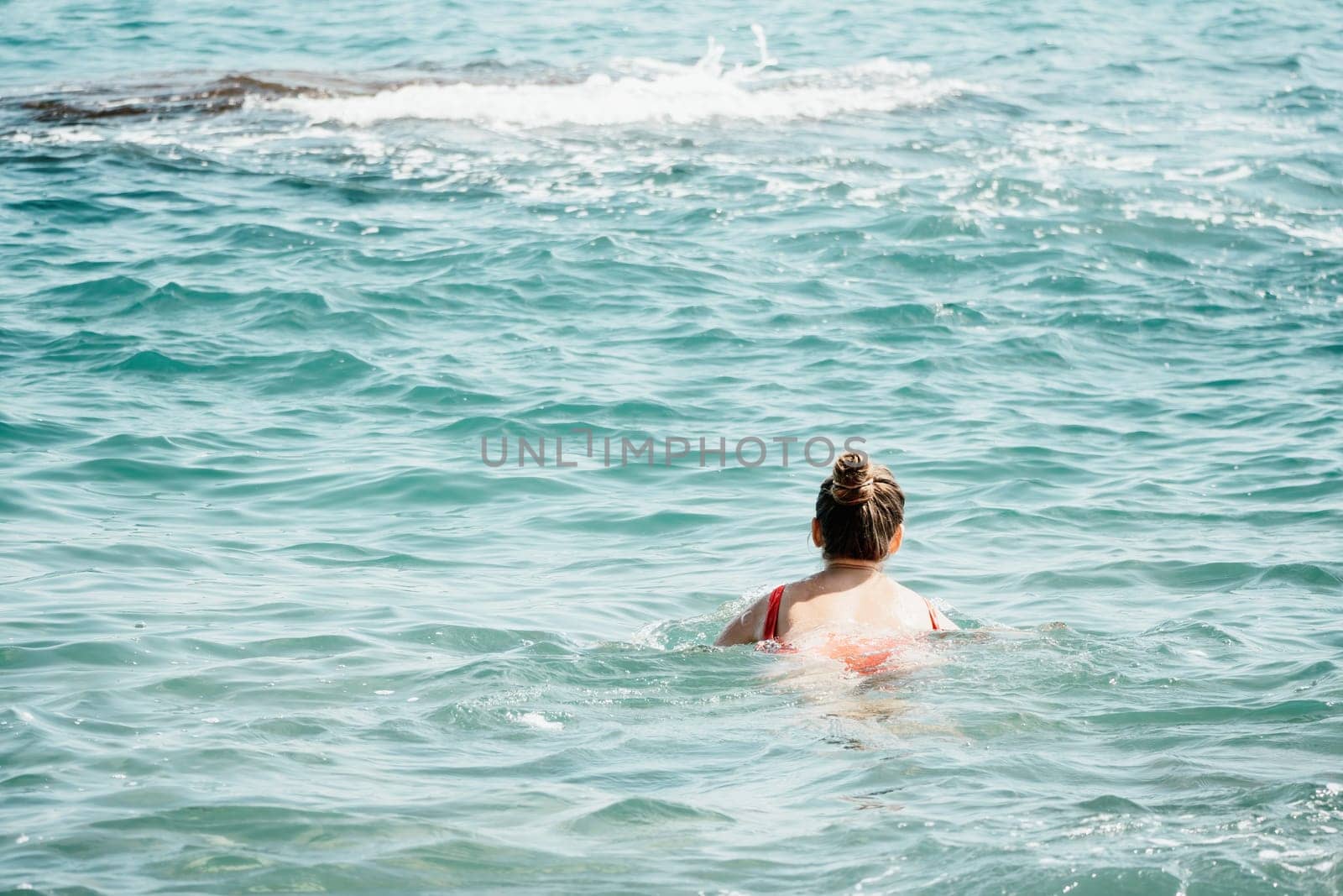 Young woman in red bikini on Beach. Happy lady in bathing suit chilling and sunbathing by turquoise sea ocean on hot summer day. Close up. Back view by panophotograph