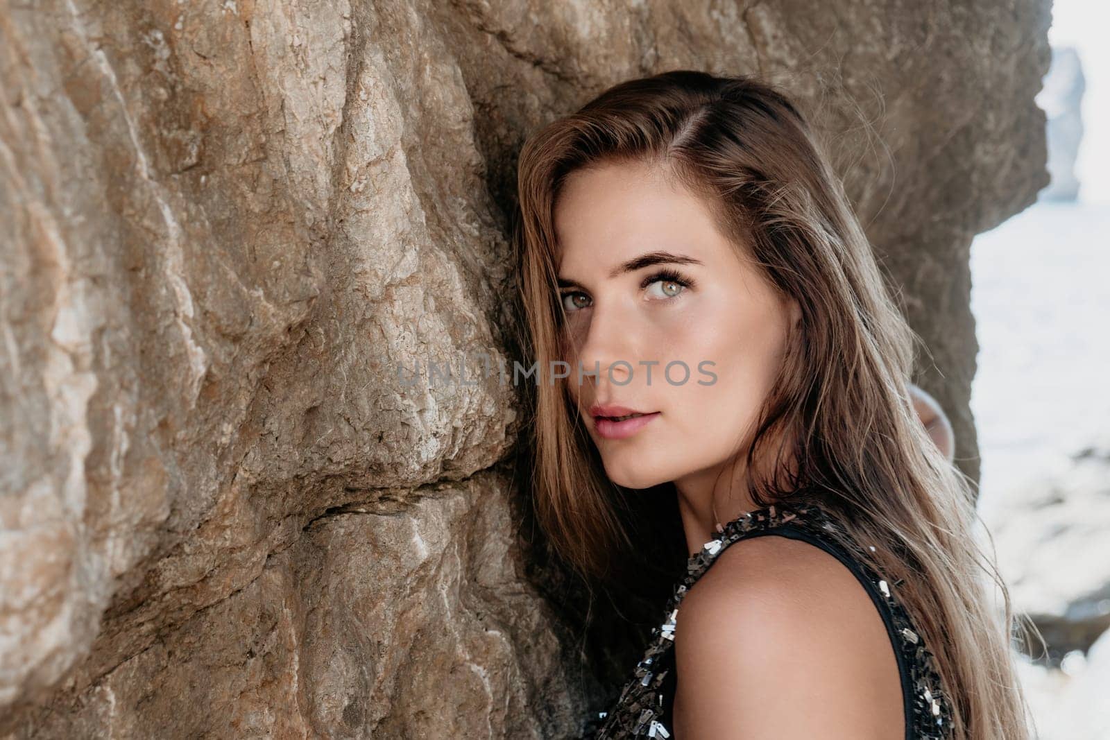 Woman travel sea. Young Happy woman in a long red dress posing on a beach near the sea on background of volcanic rocks, like in Iceland, sharing travel adventure journey