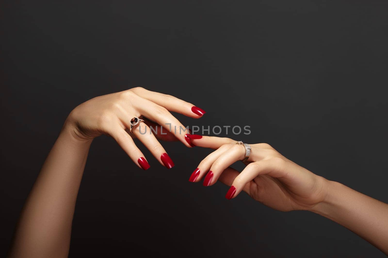Elegant female hands with bright manicure. Square nails with red gel polish. Luxury fashion style of brilliants jewelry by MarinaFrost