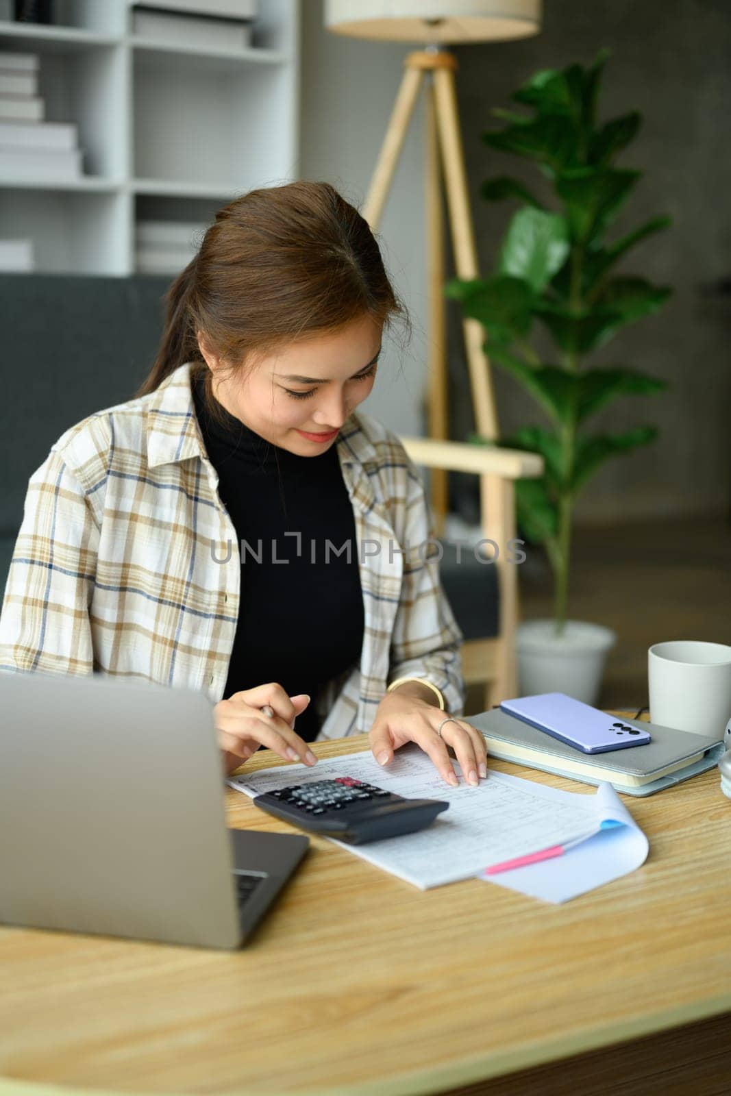 Young woman calculating domestic expenses, utility bills at home. Finance management concept.