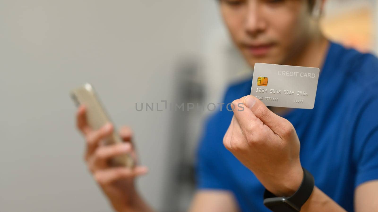 Select focus on hand holding credit card and using smartphone for making orders via iInternet or online payment.