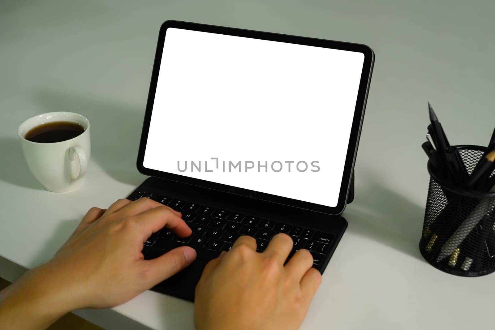 Unrecognizable hands typing of wireless keyboard of digital tablet. White empty screen for montage your graphic display.