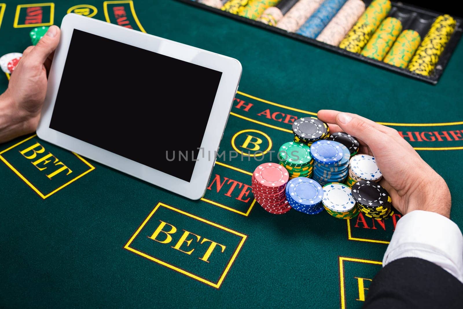 casino, online gambling, technology and people concept - close up of poker player with playing cards, tablet and chips at green casino table. first-person view. takes the prize