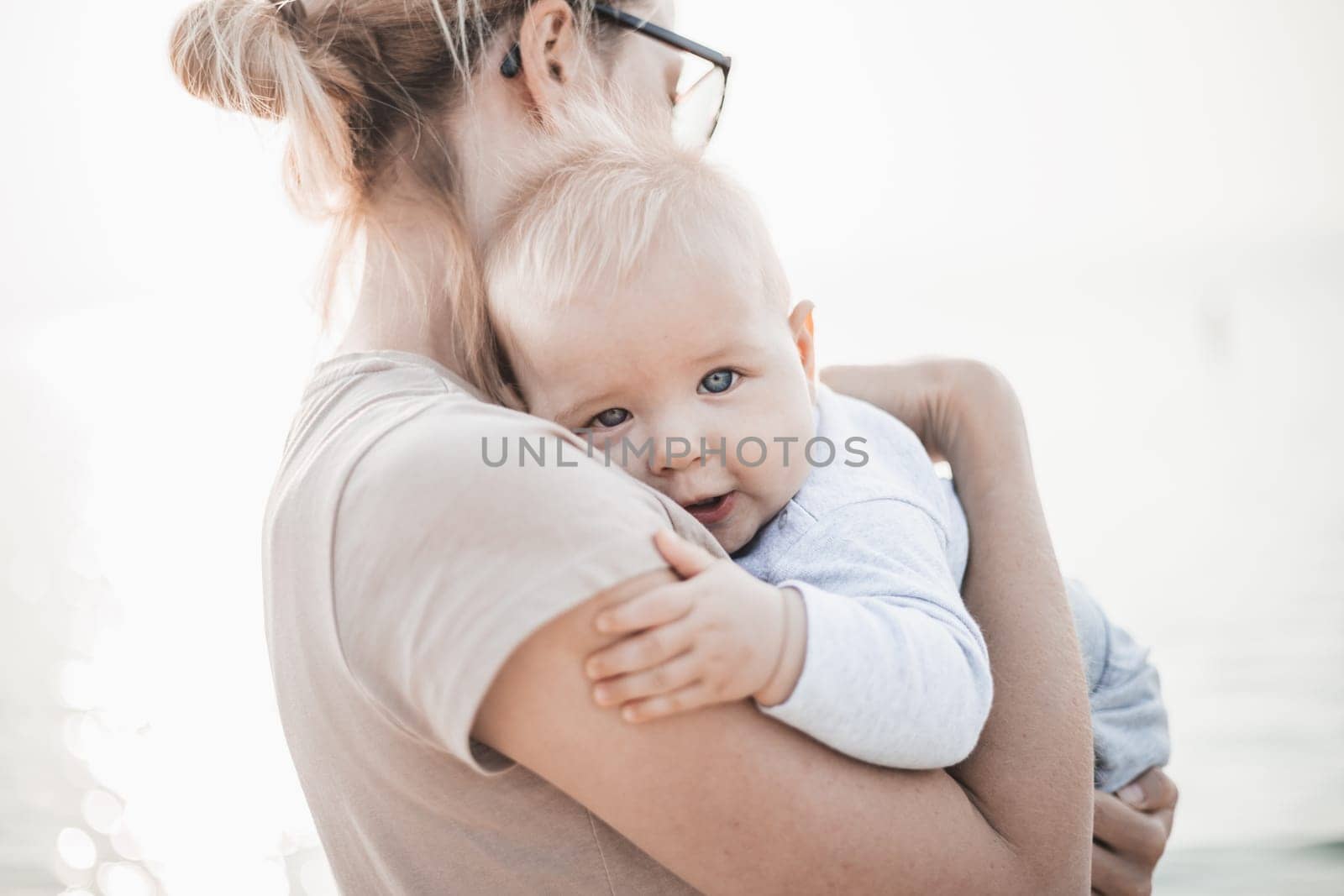 Tender woman caressing her little baby boy infant child outdoors. Mother's unconditional love for her child.