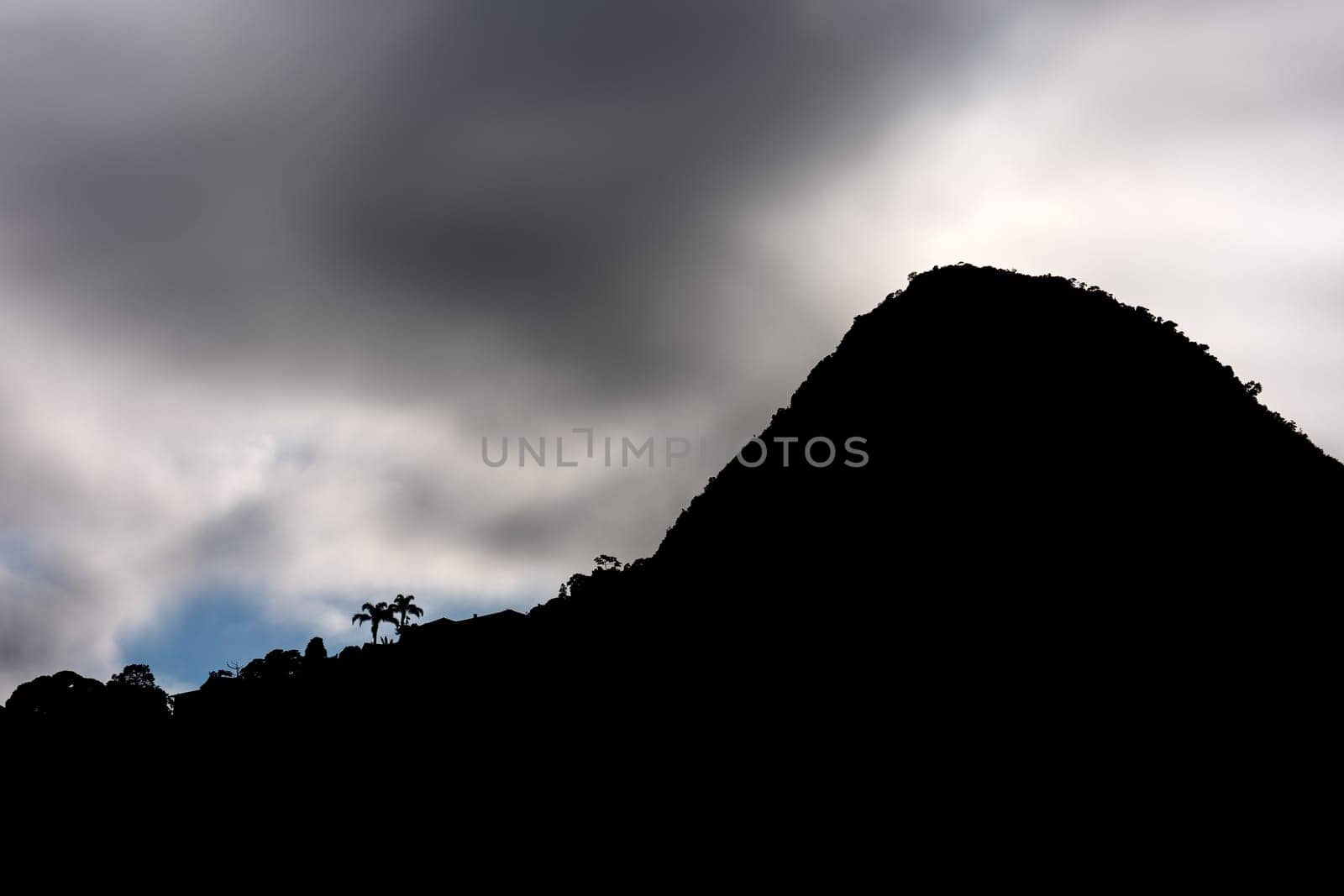 A stunning granite mountain peak stands in silhouette against a dark, impenetrable jungle sky, with space for text.