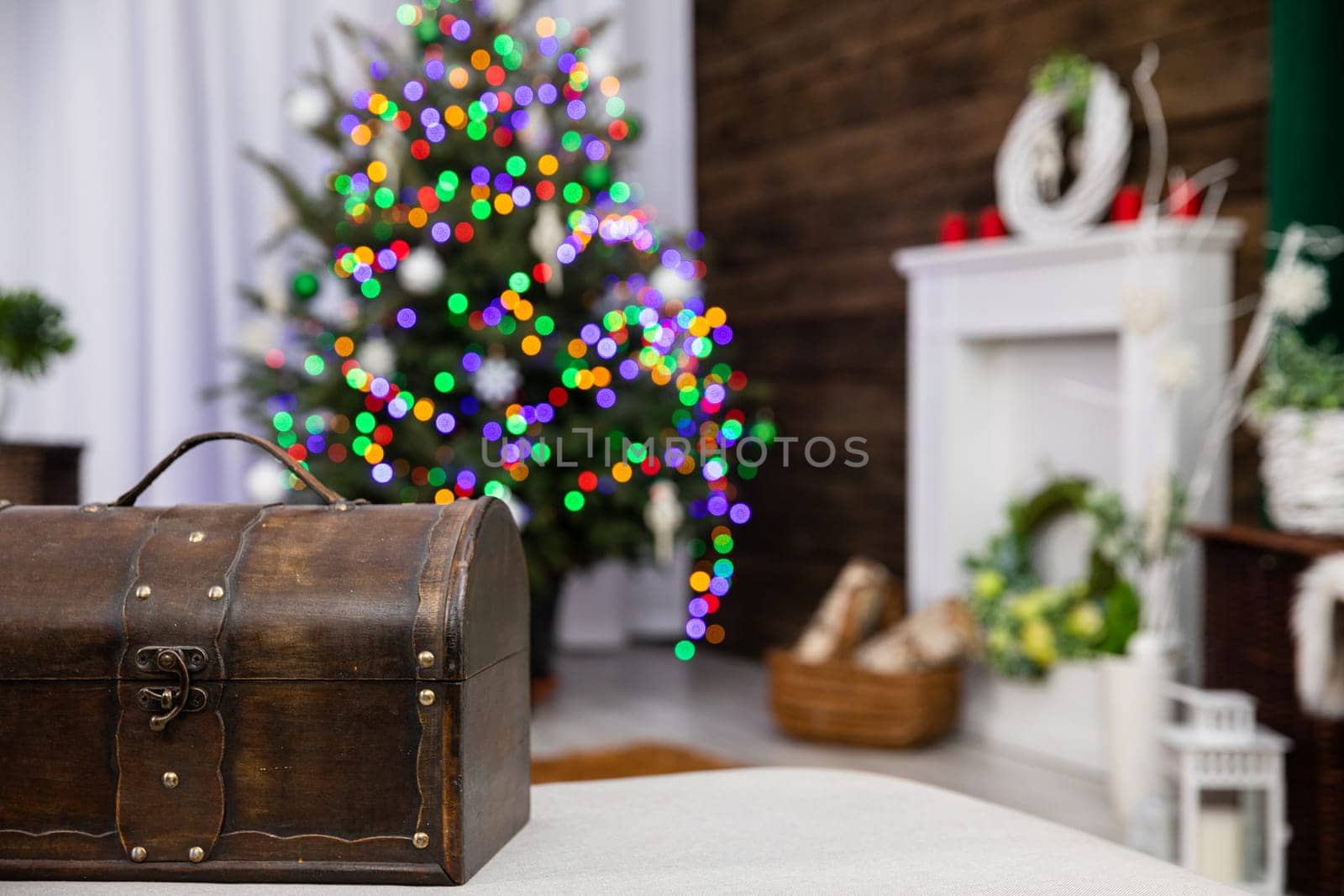 In front you can see an old brown box and against the fuzzy background stands a Christmas tree decorated with glowing Christmas tree lights.