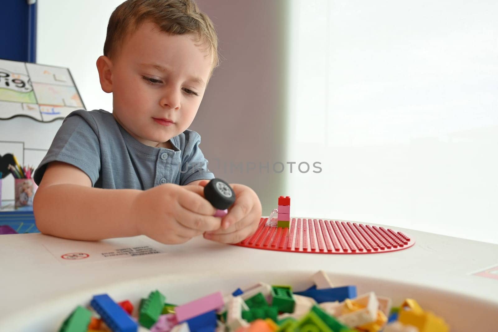 Little child playing with lots of colorful plastic toys indoor, building different cars and objects by jcdiazhidalgo