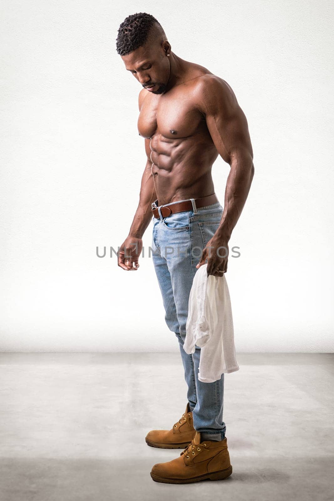 African American bodybuilder man, naked muscular torso, wearing jeans, looking down