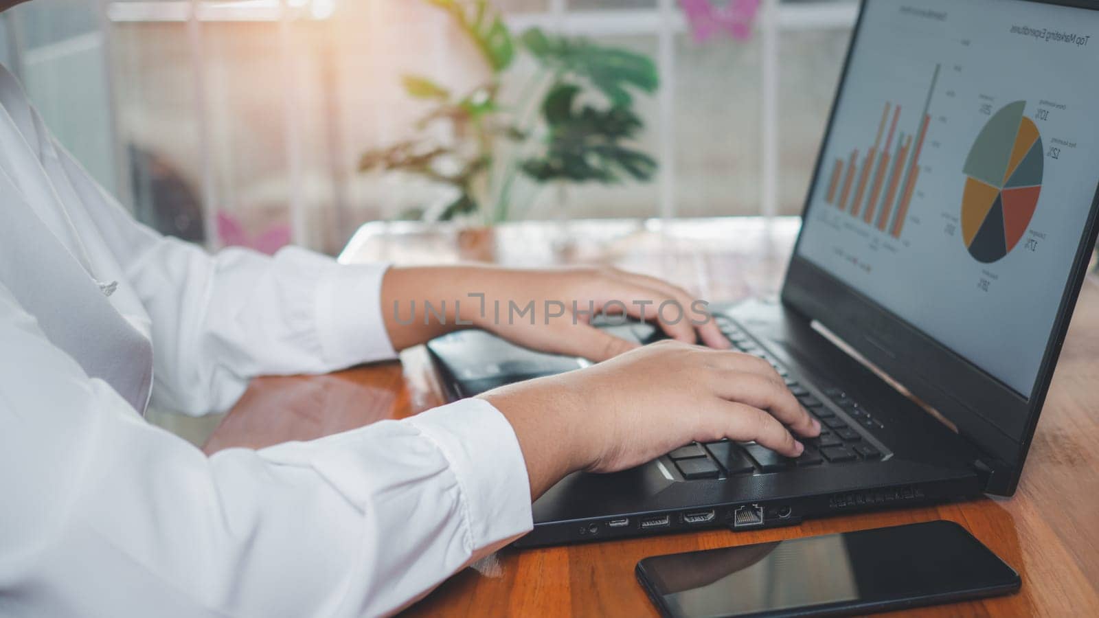 Businesswoman using laptop computer on wooden table And she is looking at the graph displayed on the computer screen. business concept