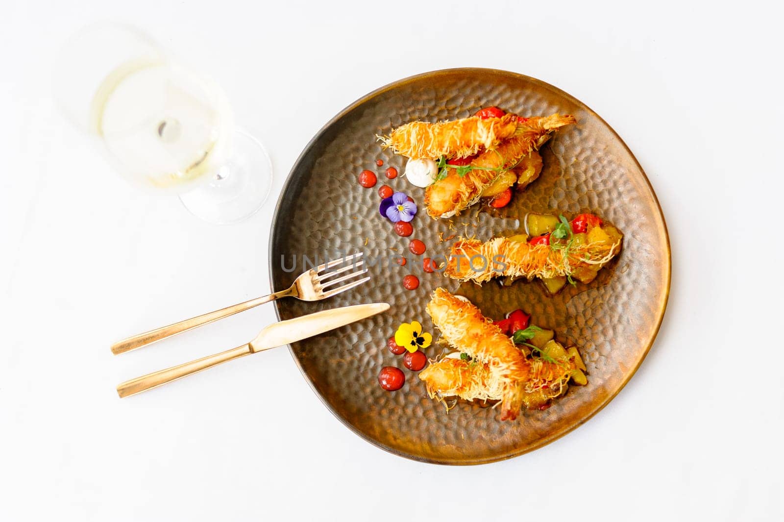 Exquisite serving of shrimps in batter on a brown plate on a white background