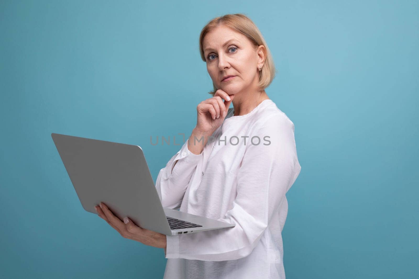 portrait of successful mature business woman with blond hair surfing the internet using laptop.