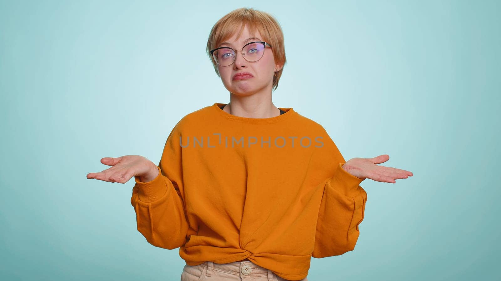 No idea, I dont know answer. Puzzled clueless uncertain attractive woman raising hands in helpless gesture, embarrassed confused by difficult question. Confused one girl on blue studio background