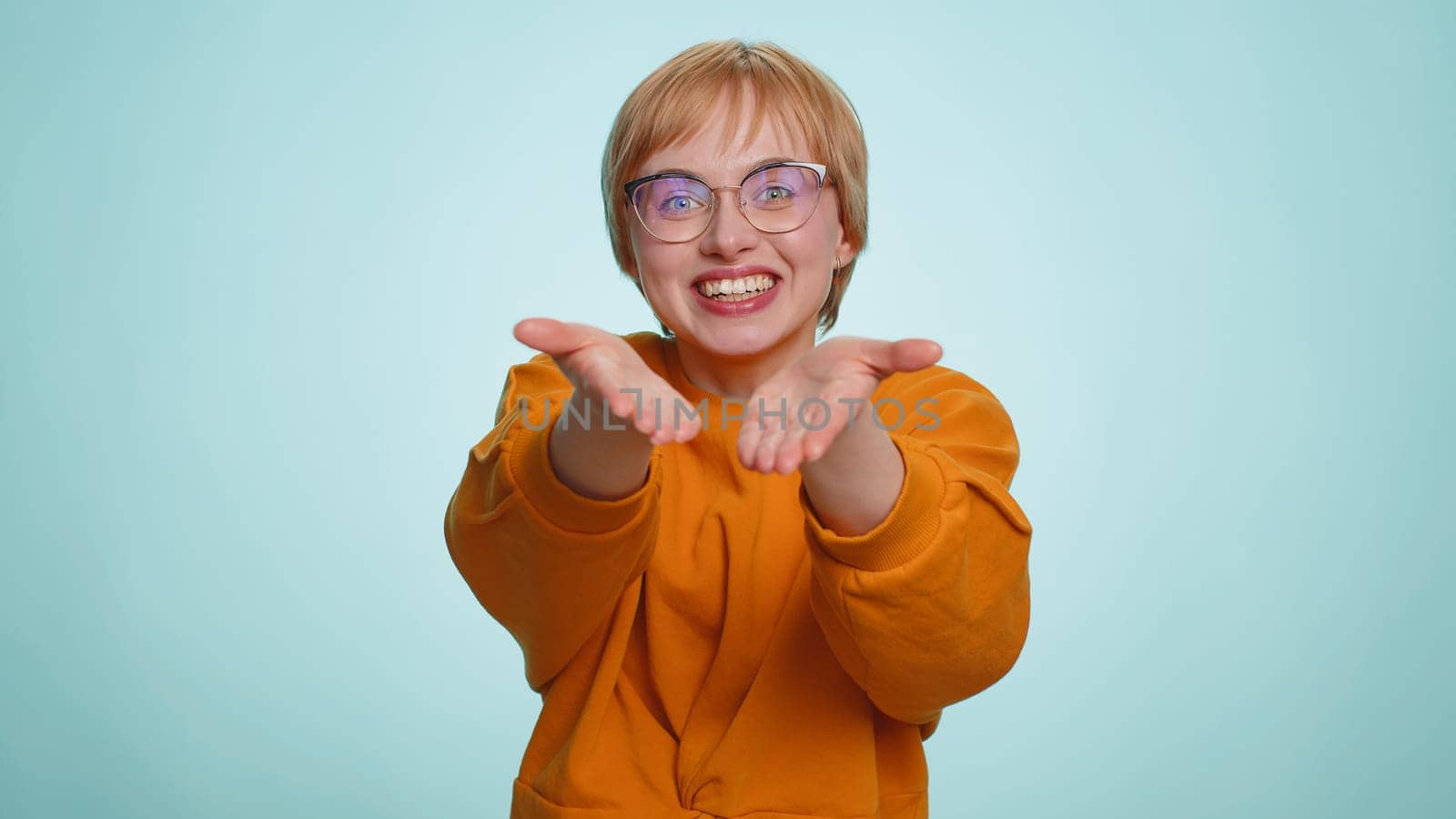 Free gifts and presents for you. Young woman opening hands, glad to see, excitement, preparing surprise, sharing love emotions, congratulating. Blonde girl isolated alone on blue studio background