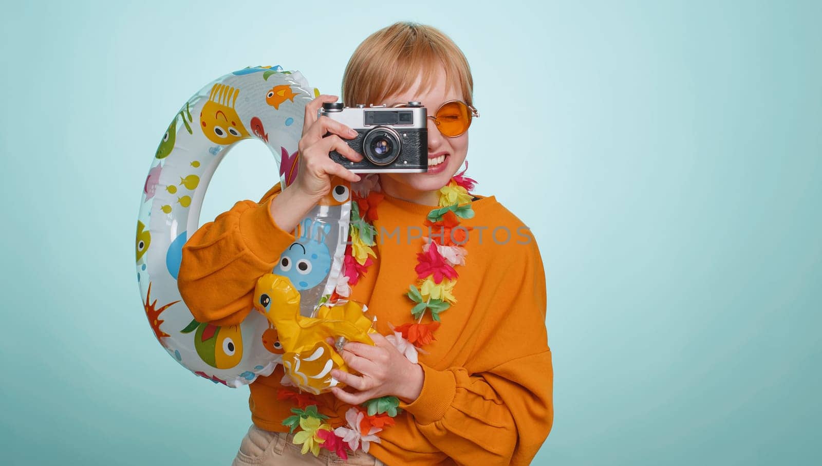 Happy woman tourist photographer in sunglasses taking pictures photos on retro camera. Travel, summer holiday vacation, trip to seaside. Pretty short haired blonde girl traveler on blue background