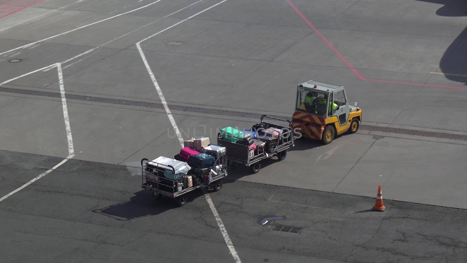 Trailer truck full of suitcases on the runway. Workers carry suitcases to load on the plane. 4k