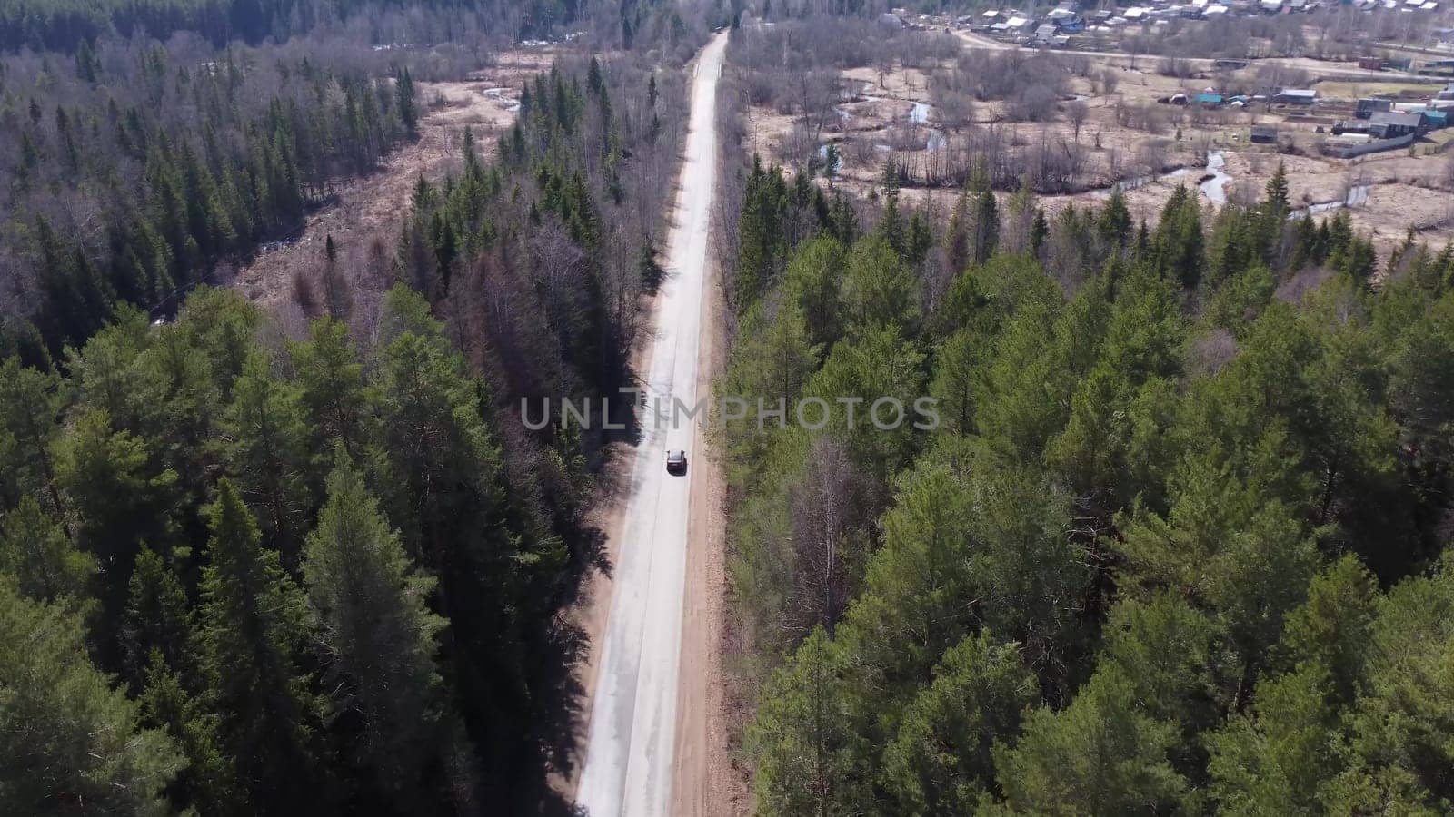 A dark car is driving along a forest road. Vehicle tracking camera. View of the car from a drone. 4k