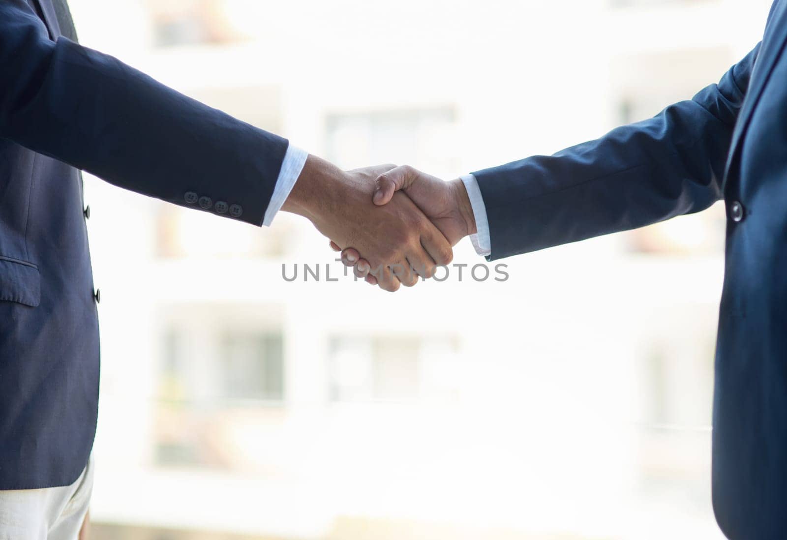 Shot of two unidentifiable businessmen shaking hands in the office.
