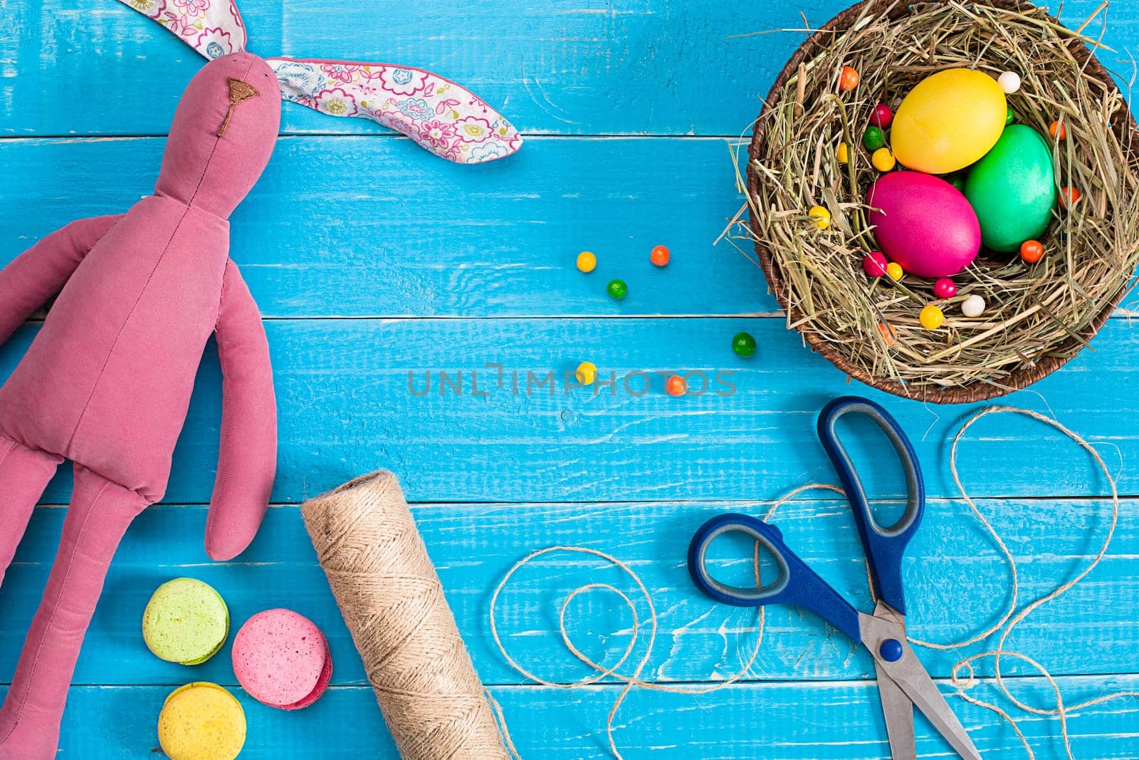 Easter eggs in nest and rabbit on blue rustic wooden planks. Still life. Top view. Copy space