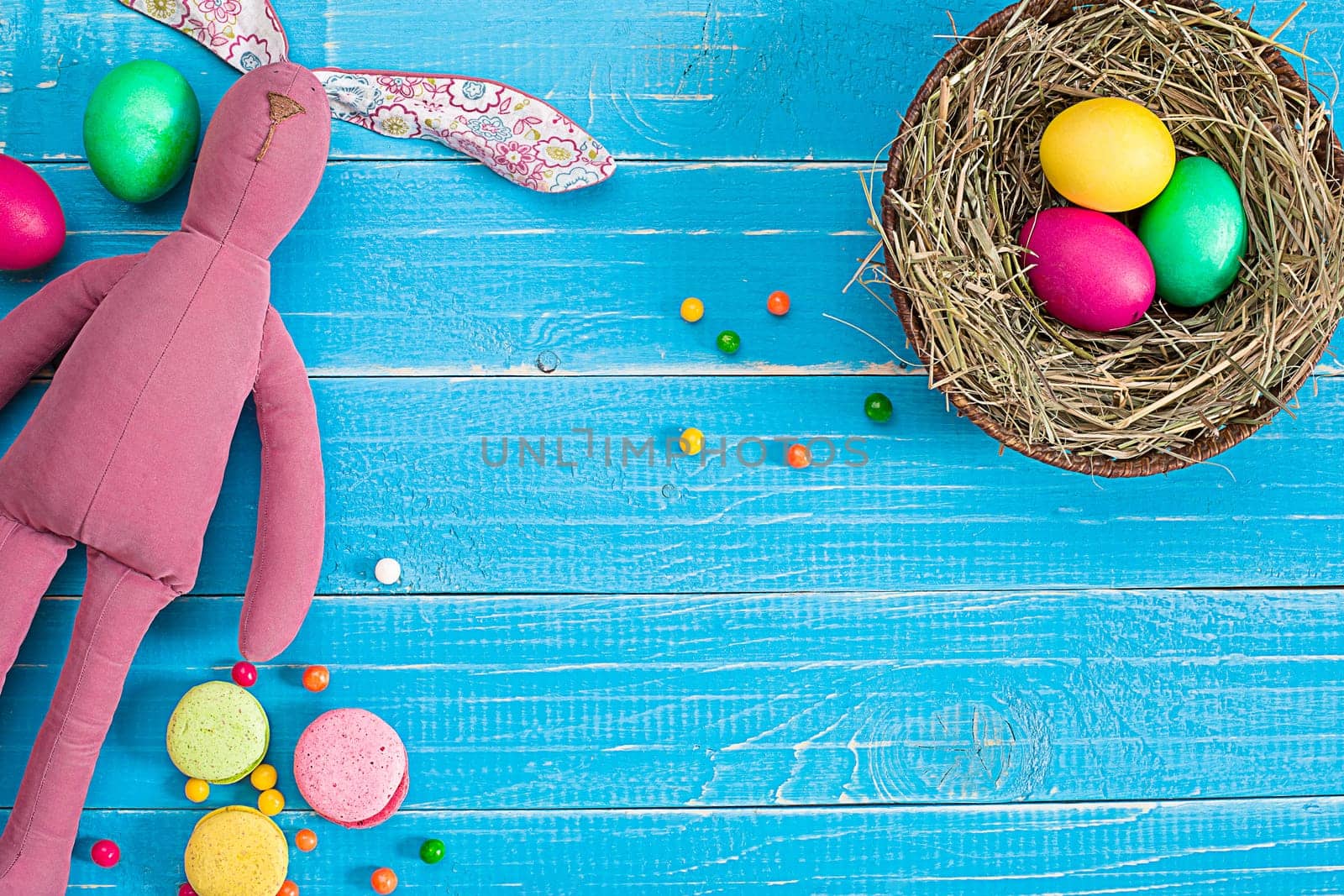 Colorful easter egg in nest on blue wood board. Background for room or space for copy, text, words.