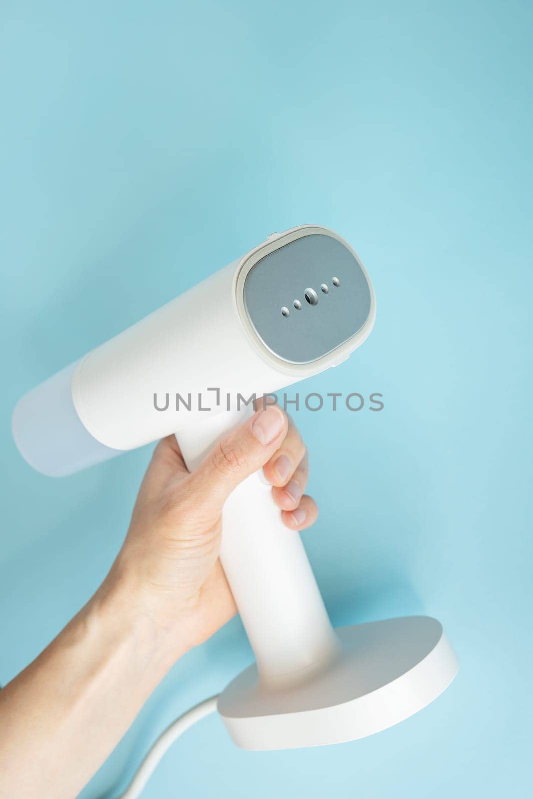 Portable home and travel clothes steamer. Steamer in the hands of a woman. Housework. by sfinks