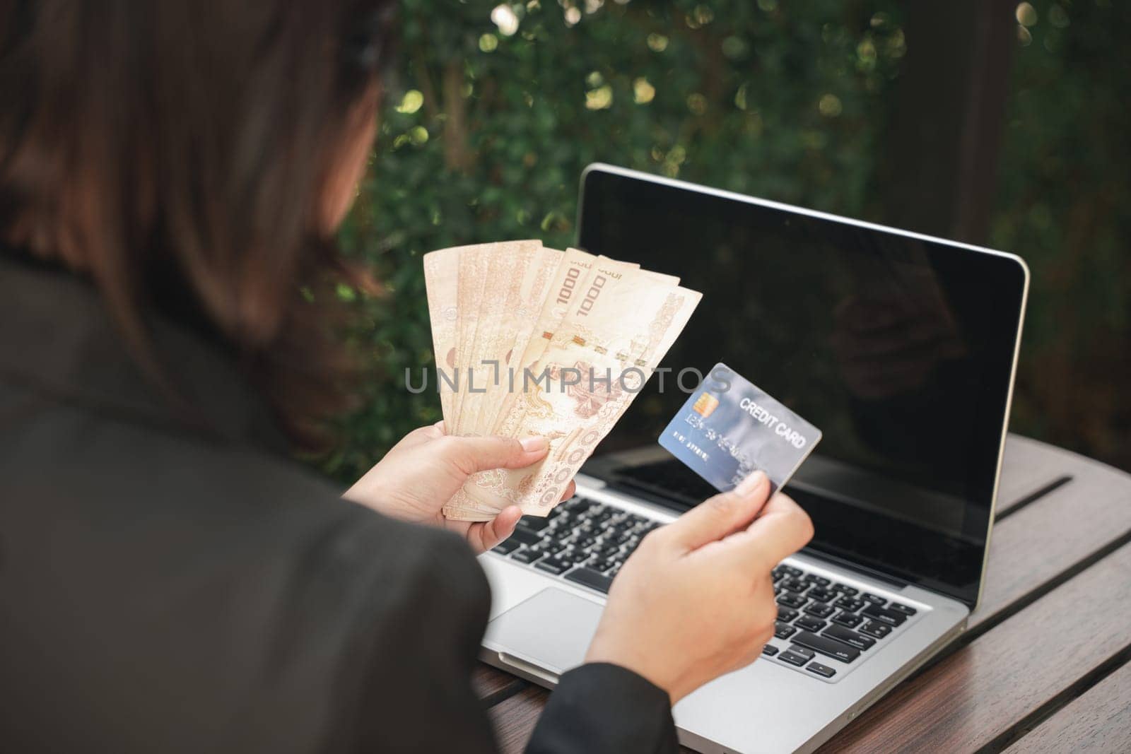 Woman using working and shopping outdoor at cafe coffee shop, Online e-commerce, internet banking, Hands of businesswoman holding thai money and credit card on laptop computer, technology finance