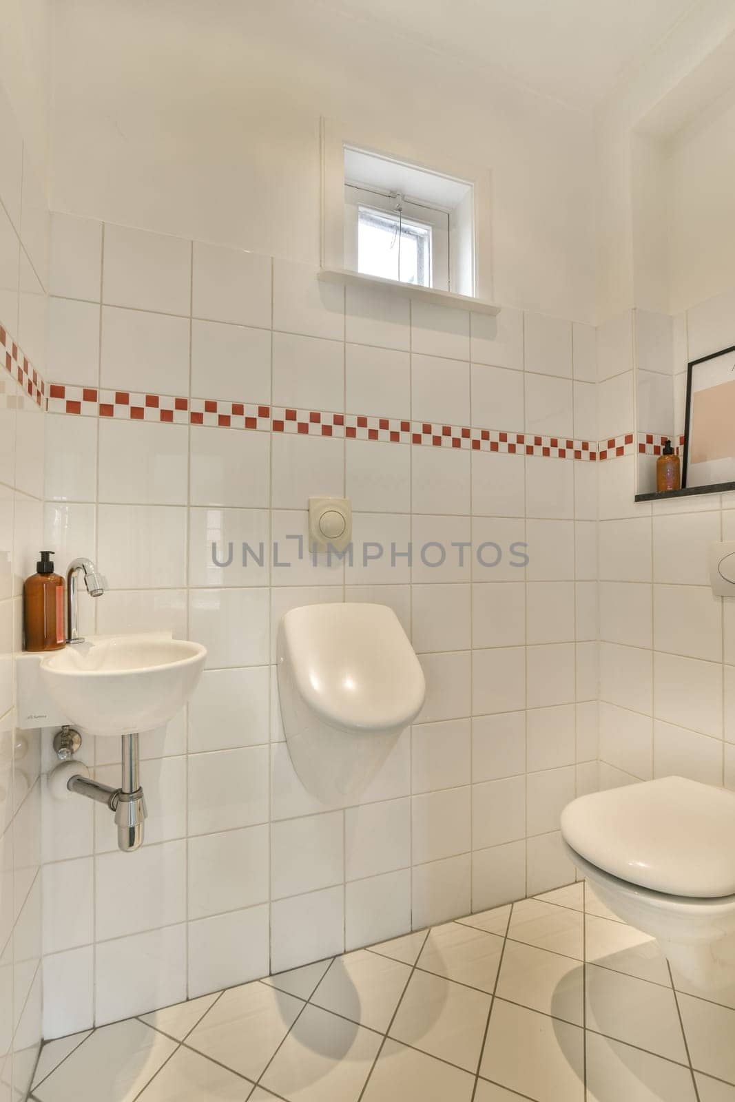 a bathroom with red and white tiles on the walls, toilet bowl, sink basin and mirror in the corner