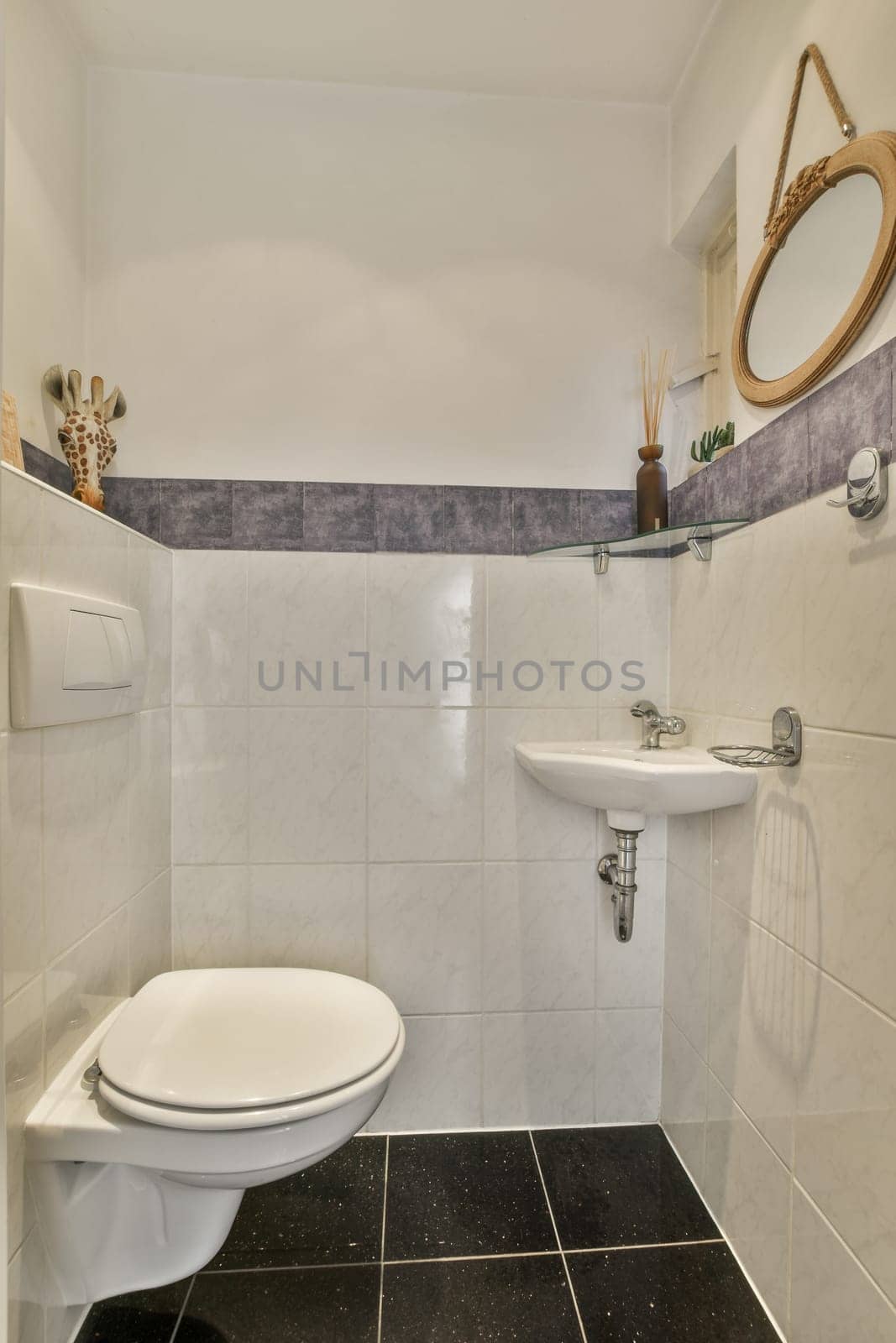 a small bathroom with black and white tiles on the floor, sink, toilet and mirror in the corner area