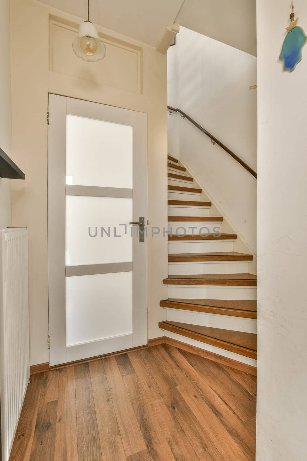 an empty room with wood flooring and white door leading up to the second floor, which is very clean