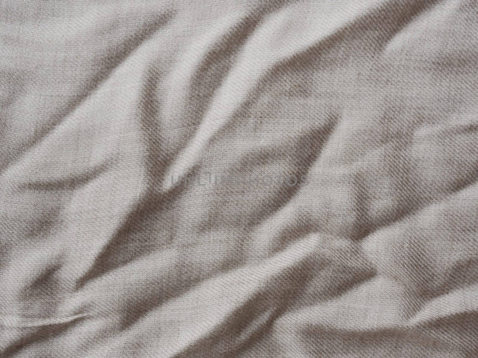 Comfortable style cloth. Minimalistic background for design. Wrinkle beige linen texture. Detailed closeup. Rustic crumpled vintage cotton fabric. Wavy folds natural material.