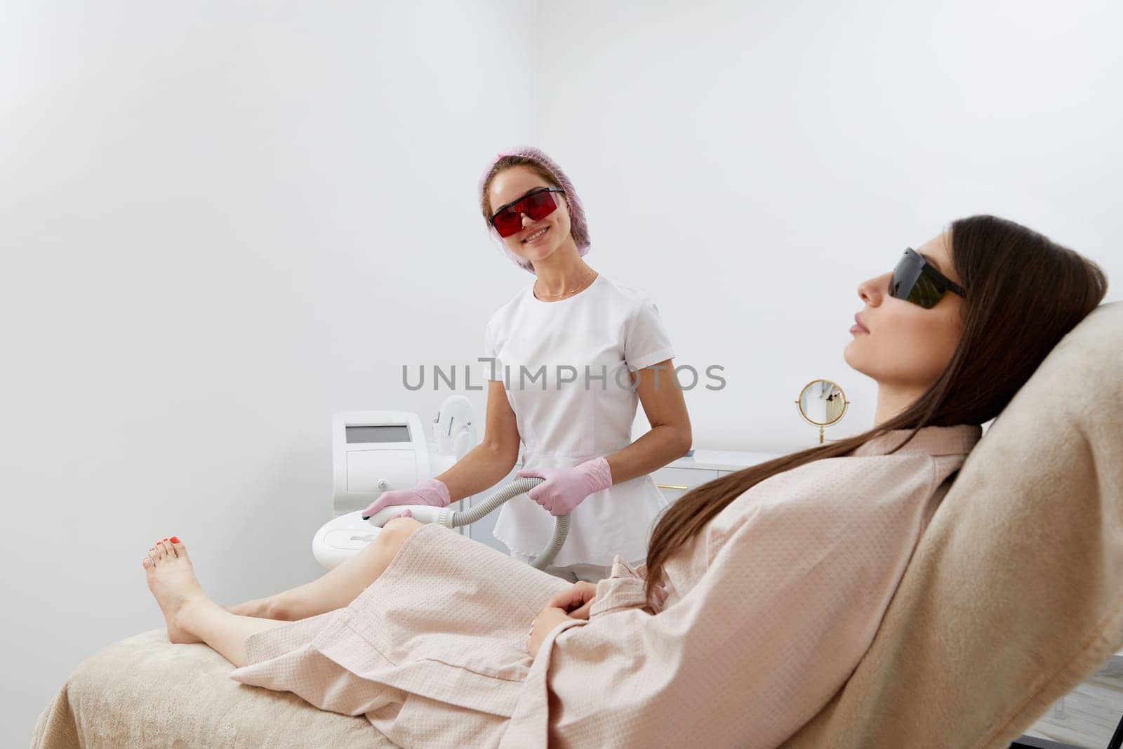 Woman receiving laser hair removal epilation on legs in a beauty salon by Mariakray
