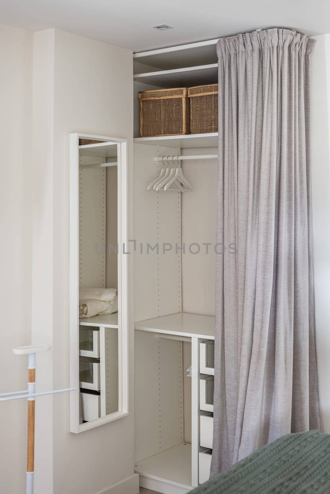 Vertical shot comfortable dressing room with gray curtain and storage space for things and clothes in the bedroom. Concept of compact but functional space in the apartment.