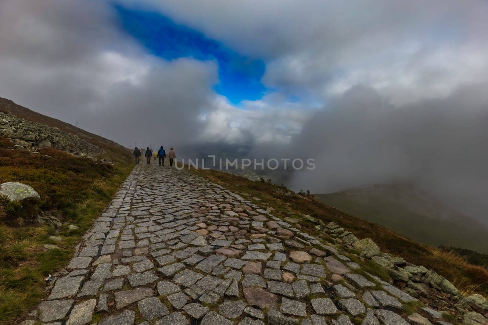 Long stony mountain trail over Sniezka mountain in Giant mountains with beautiful cloudy green landscape around