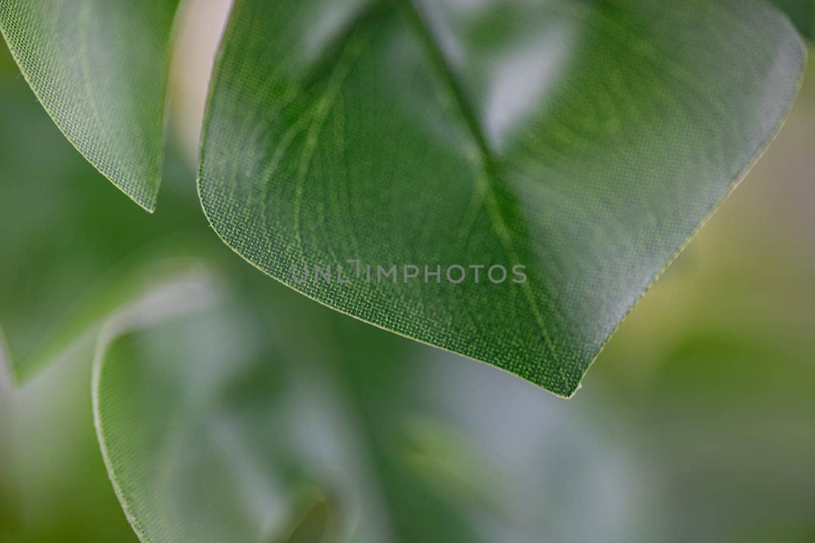 Green artificial flower with a lot of plastic leaves in gray concrete flower pot