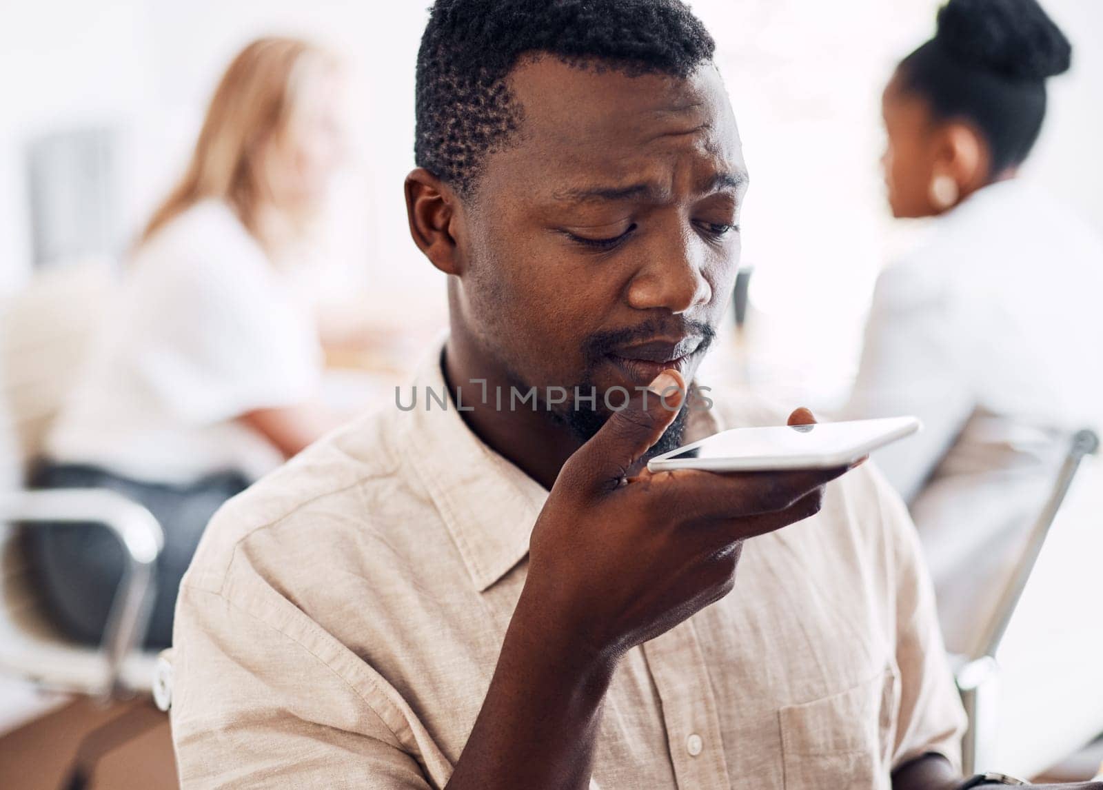 Modern technology makes communication easier. a handsome young businessman sitting in his office with his coworkers and using his cellphone. by YuriArcurs