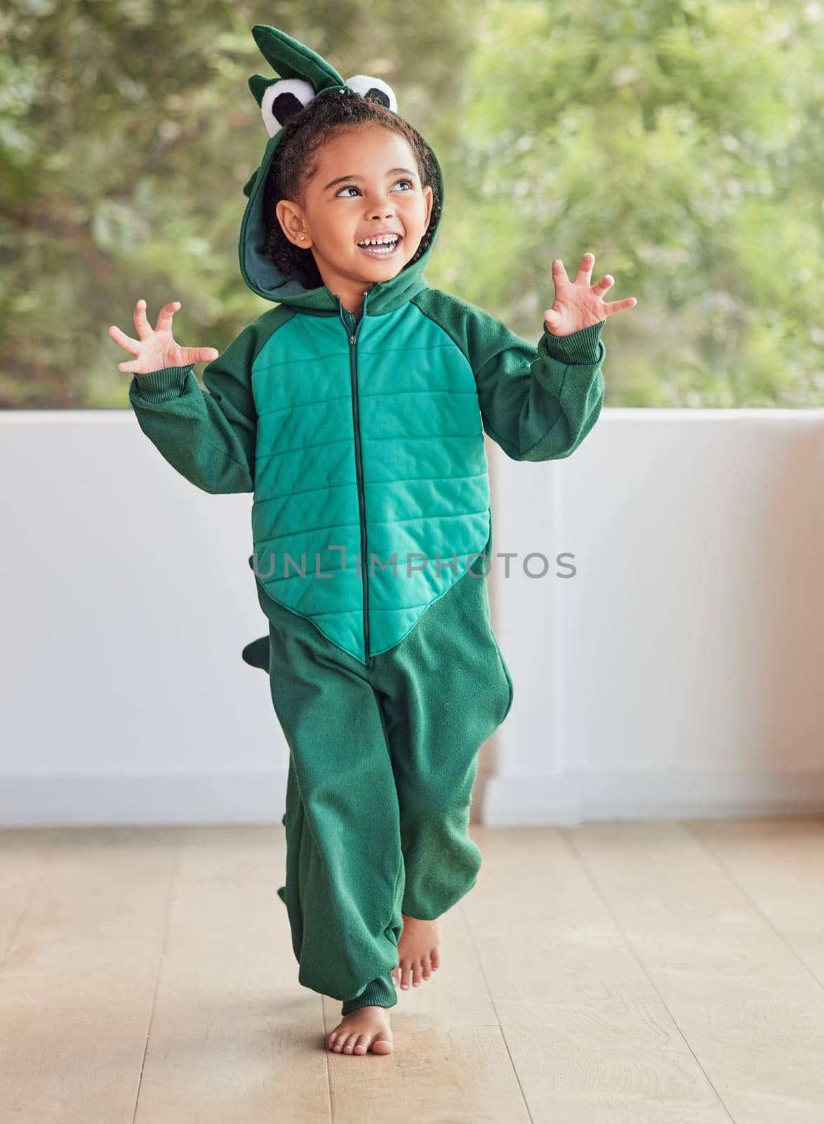 Child, smile and excited in halloween dinosaur costume at home playing role and having fun at party. Happy kid being playful with fantasy character in living room mimic animal actions ready to roar