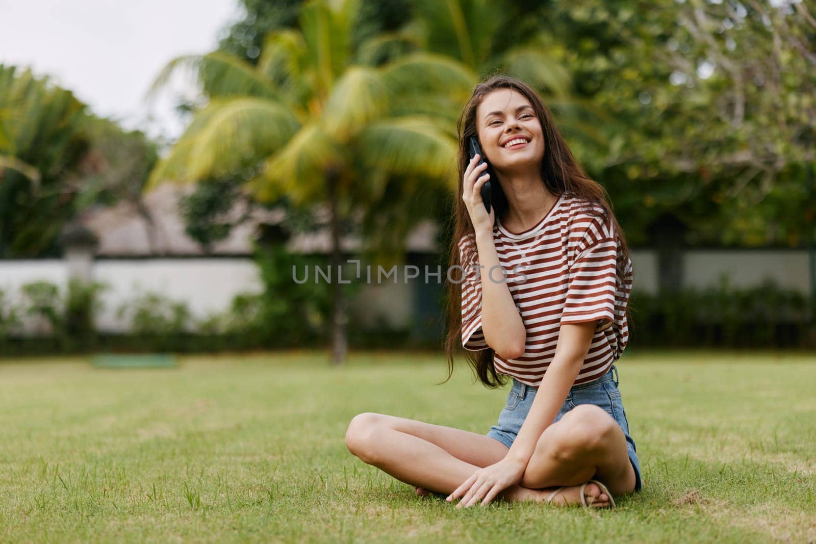 woman cellphone park application cell using phone tree grass smiling mobile browsing summer palm adult nature happy striped girl smartphone lifestyle blogger