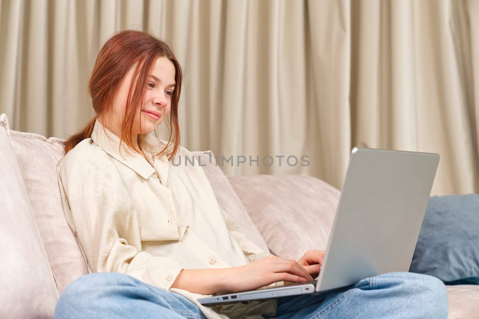 Portrait of girl in using laptop, studying online at home. Lazy day at home. Online course, doing homework