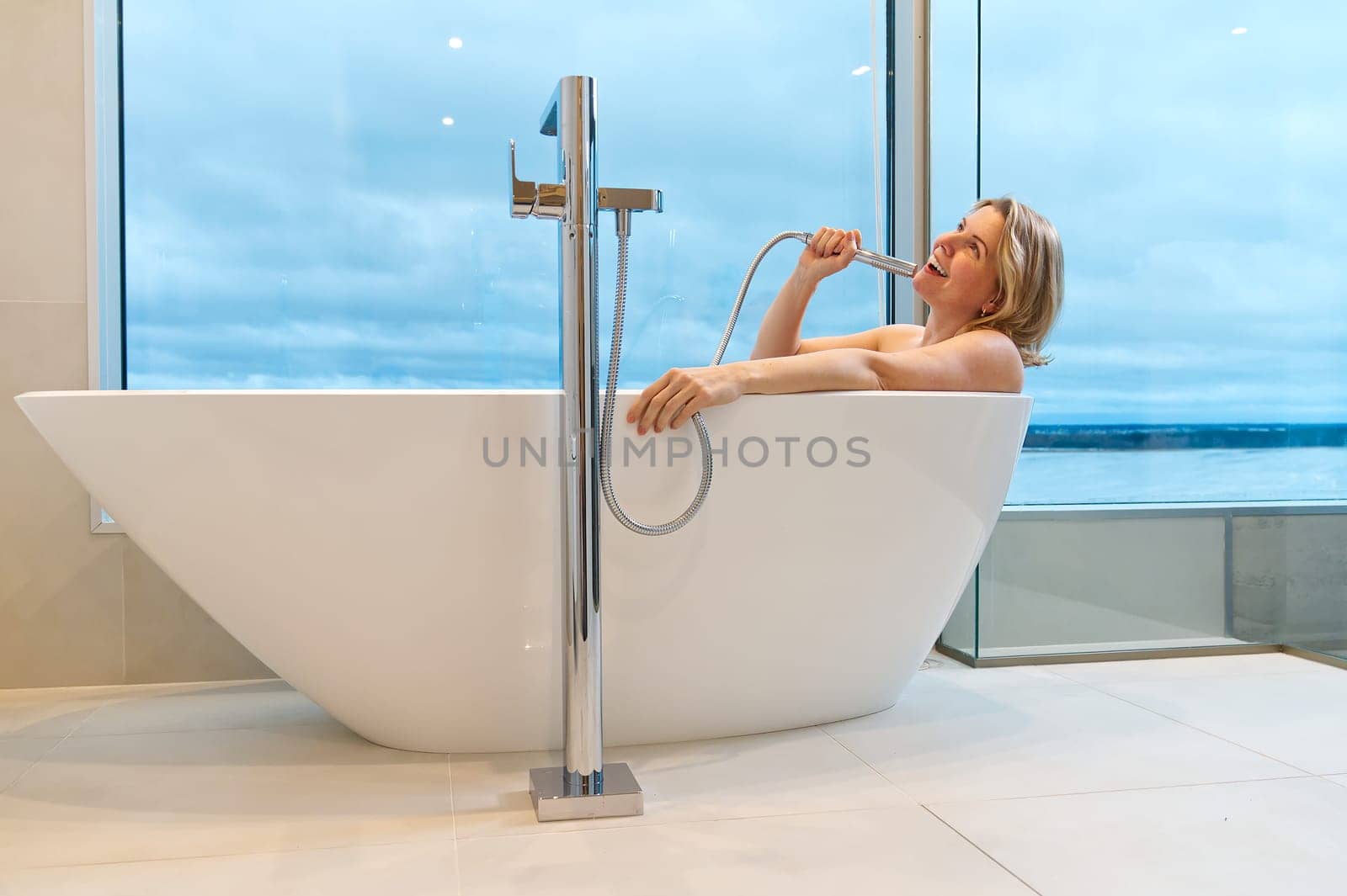 woman in freestanding white bath. Modern bathroom interior design. Beauty, healthy lifestyle concept by PhotoTime