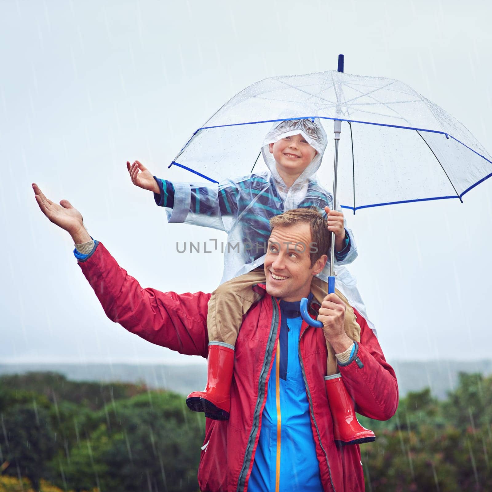 Father, child or family with an umbrella in rain outdoor for fun, happiness and quality time. Happy man and boy kid in nature with hand to catch water drops for learning, freedom and travel or play.