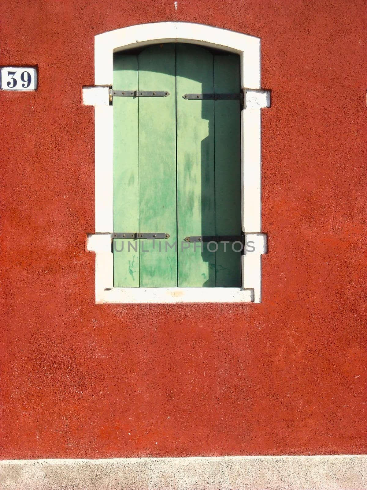 green window on red wall with white and black details