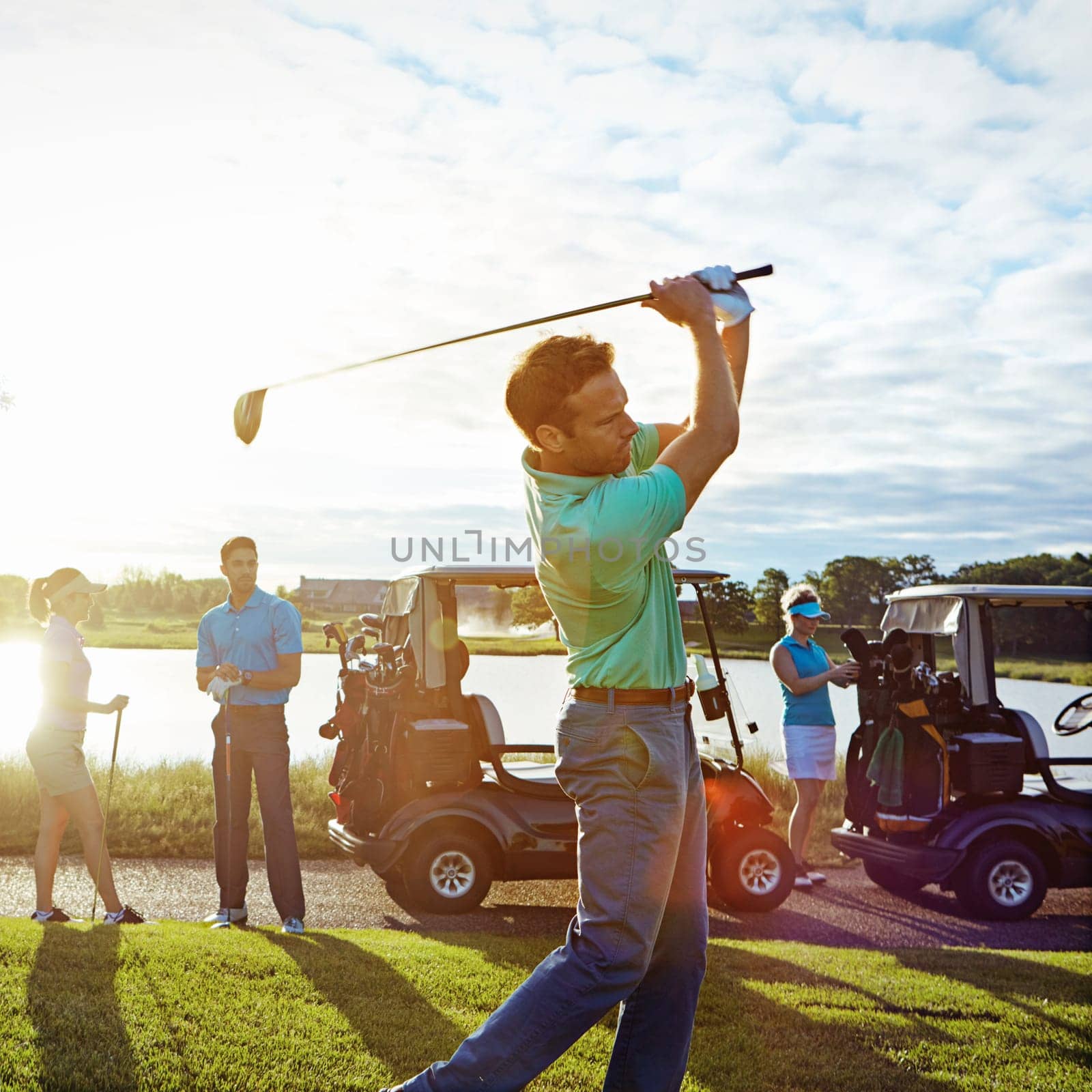 Having a swinging good time on the greens. a man playing a round of golf with his friends. by YuriArcurs