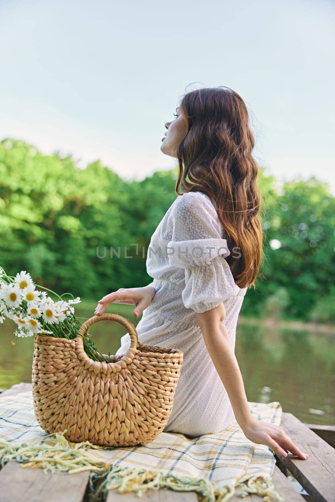 a woman with long well-groomed hair sits on the pier enjoying the view of the lake by Vichizh