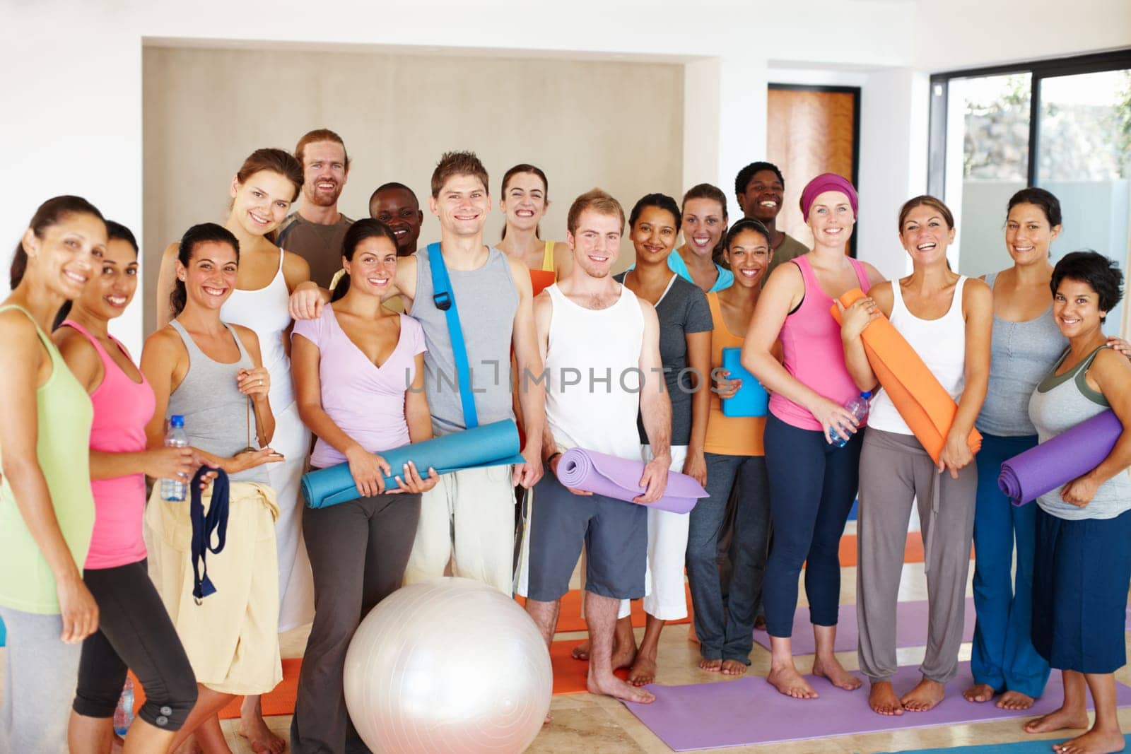 Happy in their yoga class. Portrait of a a group of yoga enthusiasts standing in a yoga studio. by YuriArcurs